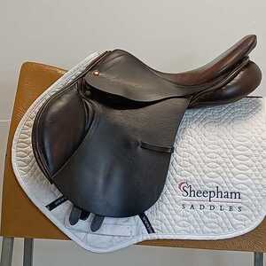 Albion 17" Jump MW Brown rests on a white saddle pad on a wooden chair.